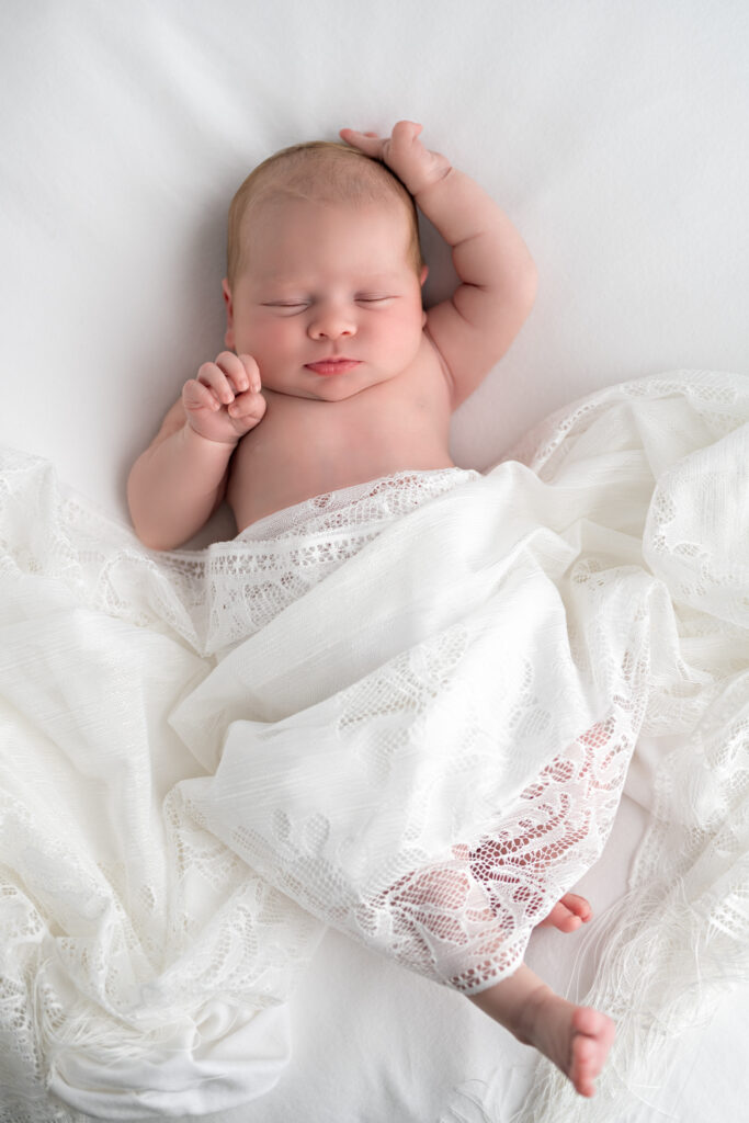 Newborn baby girl stretches during a nap at her newborn photoshoot