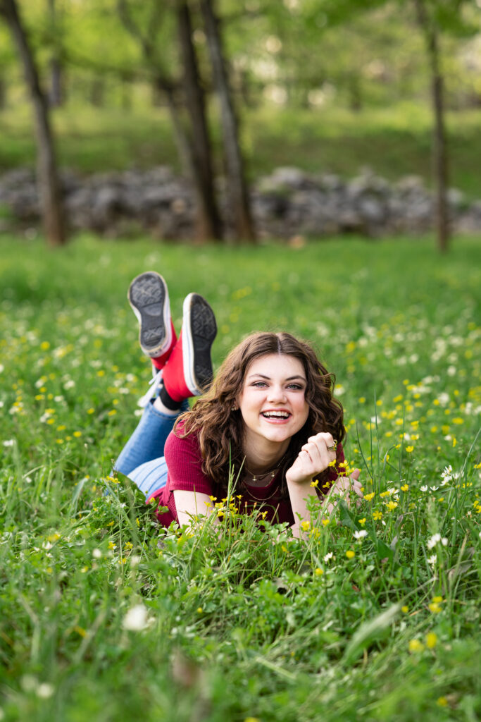 Senior girl smiles for the camera in a field of wild flowers at Hayes Nature Preserve in Huntsville, Alabama