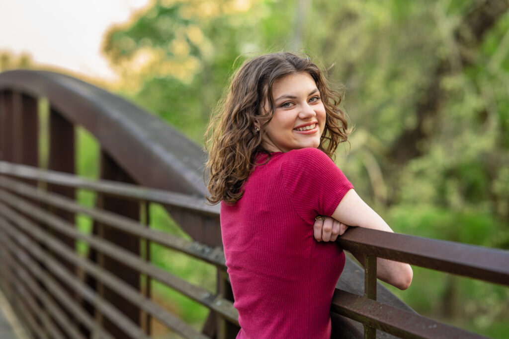 Senior girl poses for the camera on a bridge at Hayes Nature Preserve in Huntsville, Alabama