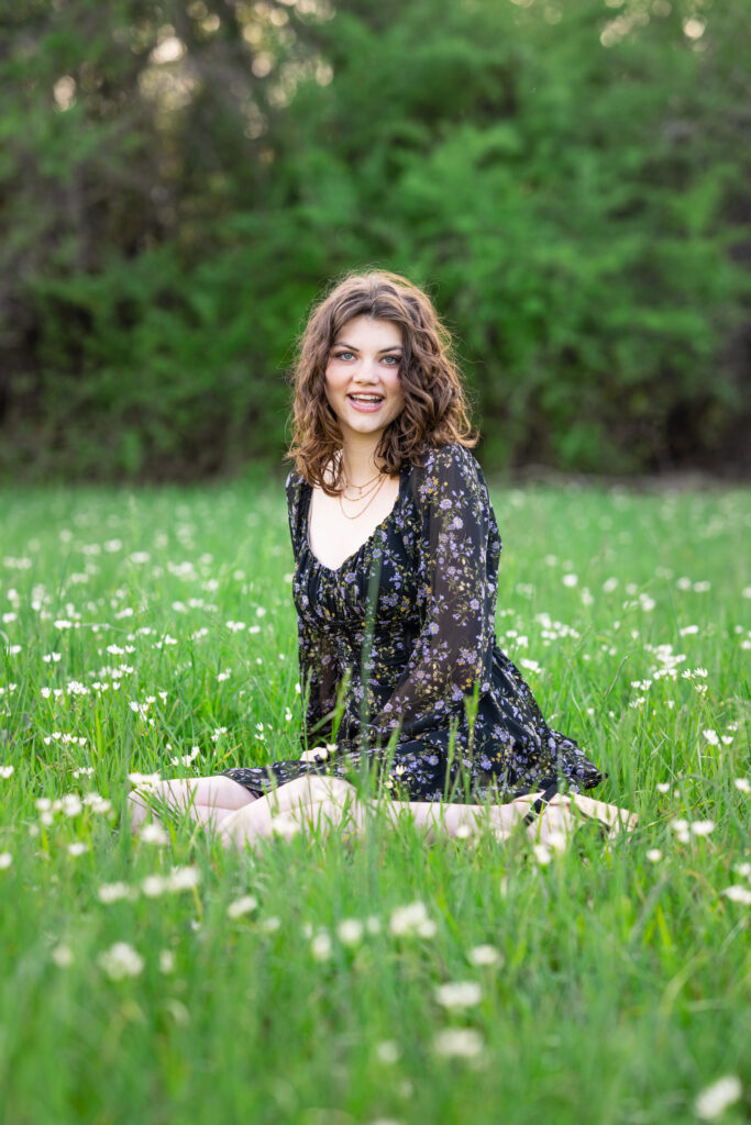 Senior girl sits in a field of wild flowers  at Hayes Nature Preserve in Huntsville, Alabama