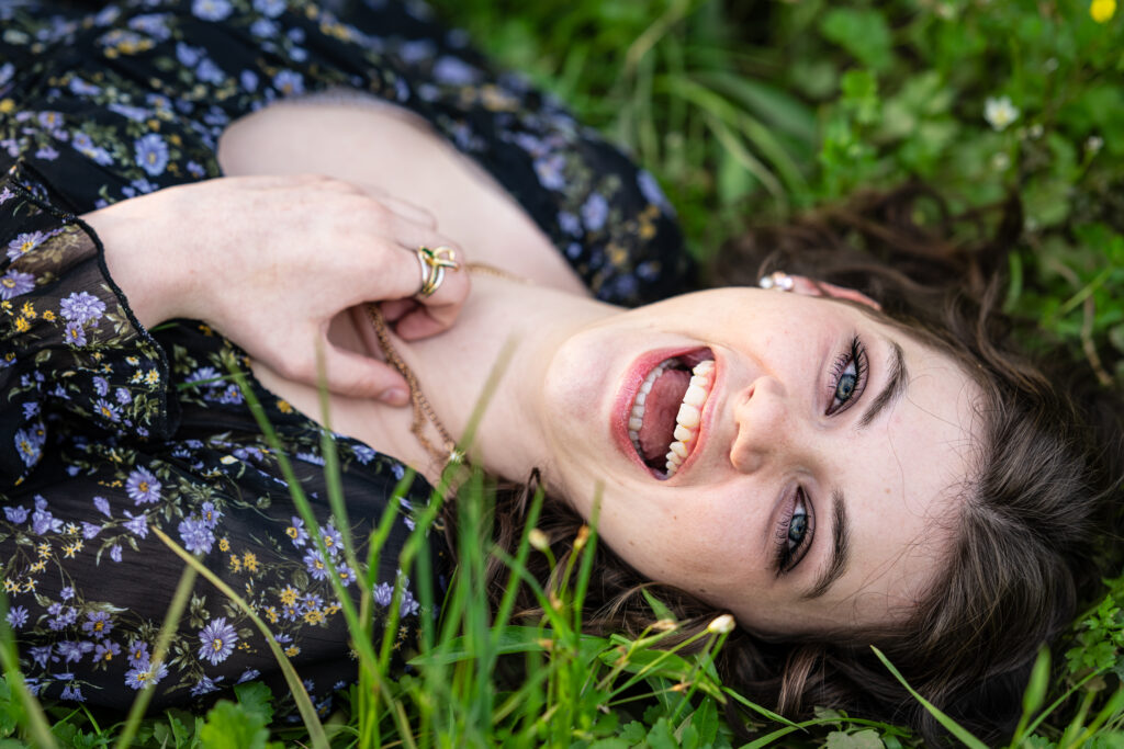 Senior girl smiles for the camera while laying in a bed of wild flowers at Hayes Nature Preserve in Huntsville, Alabama