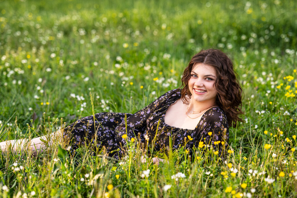 Senior girl lays in a field of wild flowers at Hayes Nature Preserve in Huntsville, Alabama