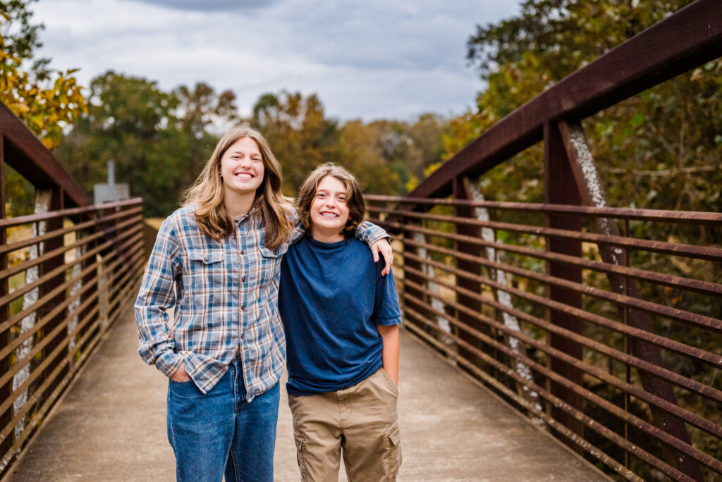 A brother and sister posing for pictures on the bridge at Hayes Nature Preserve in Huntsville Alabama