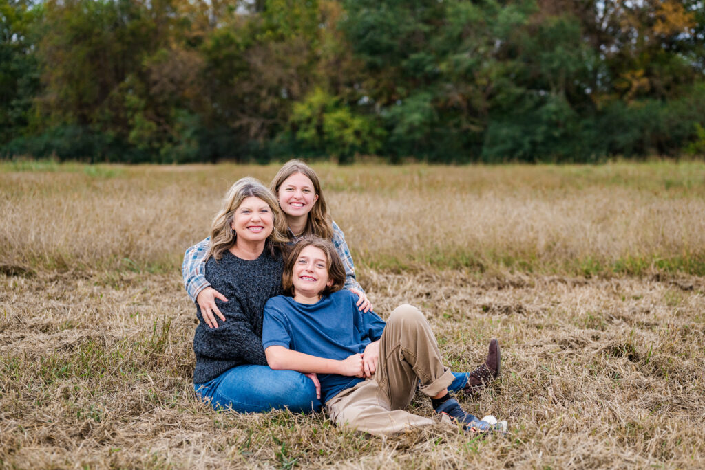 A mom and her kids sitting on the ground and posing for family picture at Hayes Nature Preserve in Huntsville Alabama