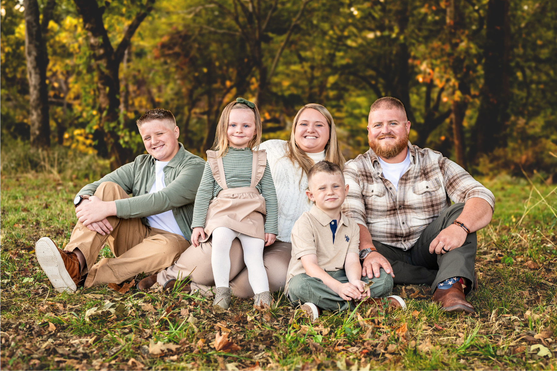 A family of five posing on the ground together for family photos at Hayes Nature Preserve in Huntsville Alabama